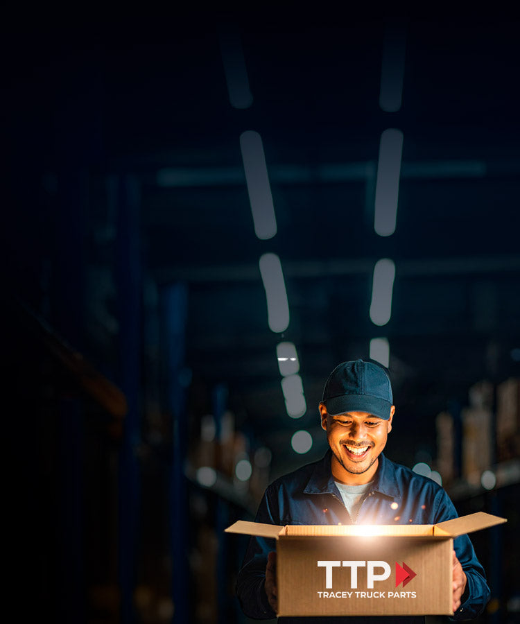 Person opening a box labeled TTP Tracey Truck Parts in a dark setting